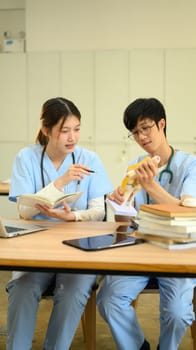 Medical students in blue scrubs studying an anatomical mode in modern study area.