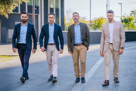 Four businessmen in smart and formal attire walking outdoors in an urban setting, exuding confidence, teamwork, and professionalism.