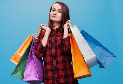 A happy young woman poses confidently with multiple colorful shopping bags.