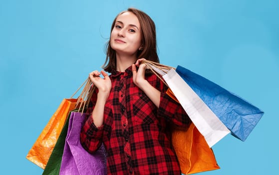 A cheerful young woman is showcasing an array of colorful shopping bags, highlighting the joy of shopping.