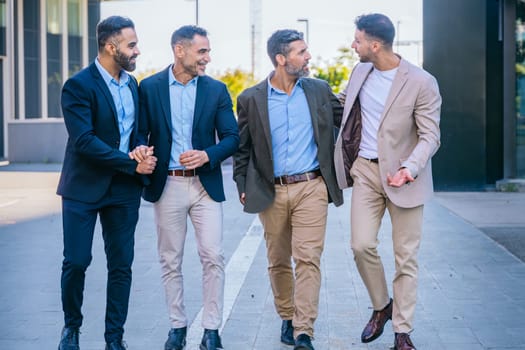Four businessmen in smart and formal attire walking outdoors in an urban setting, engaged in conversation and showcasing teamwork and professionalism.