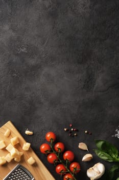 Vertical card with fresh Italian ingredients with basil, tomatoes, garlic and cheese on a dark background. Place for your text.