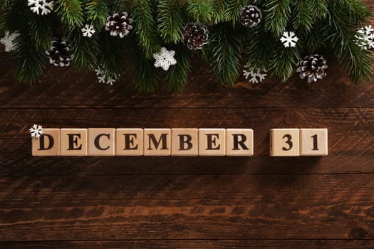 Date December 31 on dark wooden background with spruce branches, pinecones and snowflakes. Festive background.