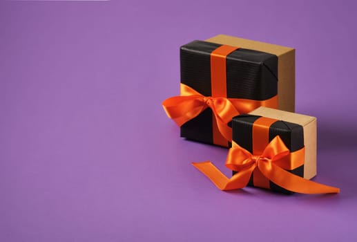 Banner with black gift boxes with orange ribbon on purple background. Space for your text. Selective Focus.