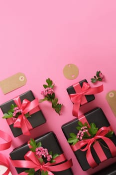Set of black craft gift boxes with hawthorn flowers and pink ribbons. Vertical, space for your text.