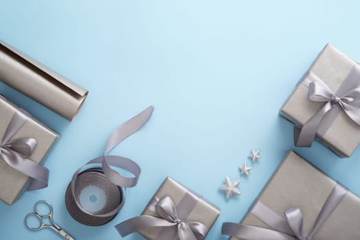 Banner with gift wrapping. Gray paper, silver ribbon, scissors on light blue background. Horizontal, copyspace