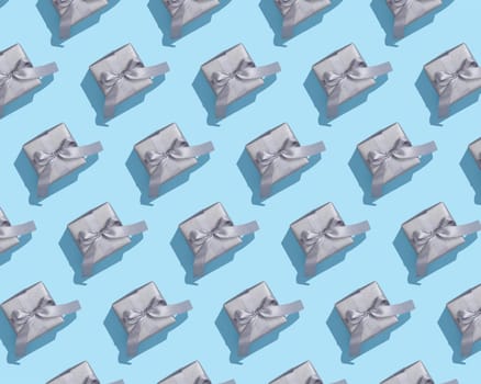Pattern of silver gift boxes on with gray bows on blue background