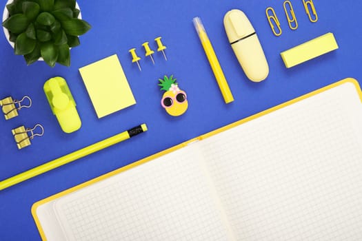 Part of blank notebook page for your text with yellow school and office stationery on blue background. Flatly.