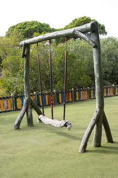 Large playground swings made from solid tree trunks. Mid shot