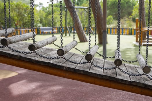 Wooden installation on the playground - wooden beams hung on chains. Mid shot