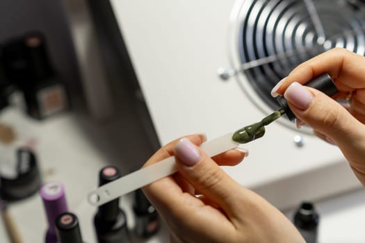 A manicurist applies gel nail polish to empty tips as a sample for future clients. Large range of gel polishes. Spa body care concept. Nail technician