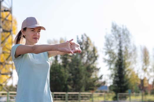 A young beautiful woman in sportswear plays sports at a local stadium. Exercise, jog and exercise at the beginning of the day. Healthy and active lifestyle.