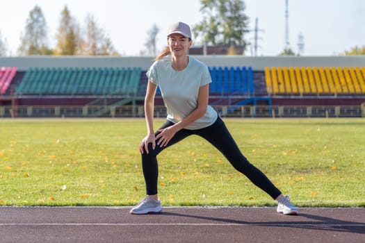 A young beautiful woman in sportswear plays sports at a local stadium. Exercise, jog and exercise at the beginning of the day. Healthy and active lifestyle.