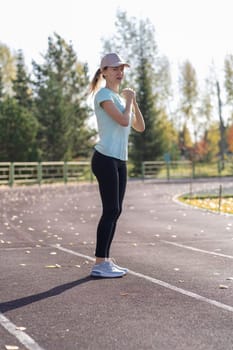 A young beautiful woman in sportswear plays sports at a local stadium. Exercise, jog and exercise at the beginning of the day. Healthy and active lifestyle.