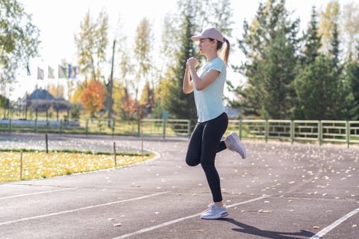 A young beautiful woman in sportswear plays sports at a local stadium. Exercise, jog and exercise at the beginning of the day. Healthy and active lifestyle.