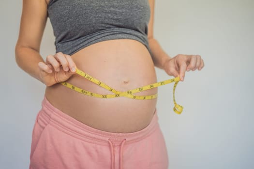 Young woman measuring her pregnant belly with inch tape. Inches, American standard. Preparation for childbirth, Girl big belly advanced healthy pregnancy.