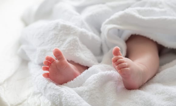 Tiny feet of the baby subtly appearing from a soft white towel reflecting the warmth and innocence after a soothing bath