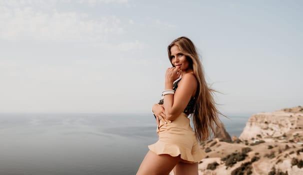 Woman travel sea. Happy tourist taking picture outdoors for memories. Woman traveler looks at the edge of the cliff on the sea bay of mountains, sharing travel adventure journey.