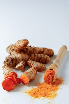 fresh turmeric root and ground turmeric on a wooden spoon isolated on white background and copy space