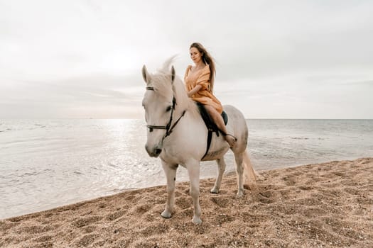 A woman in a dress stands next to a white horse on a beach, with the blue sky and sea in the background