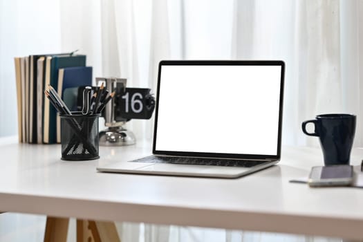 Home office desk with laptop computer, coffee cup and pencil holder.