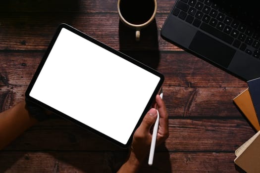 Above view of man hands holding pen and digital tablet over wooden desk. Empty display for advertising text message.