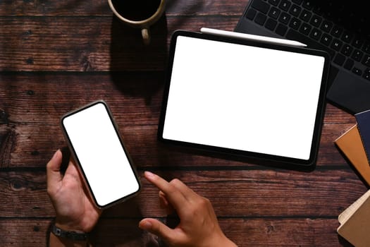 Top view of woman using smart phone over wooden working desk. Screen for your advertising text message.