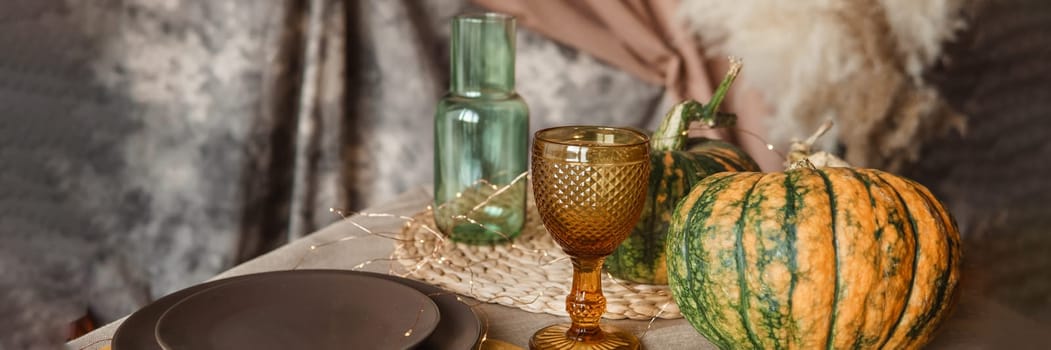 Autumn interior: a table covered with dishes, pumpkins, a relaxed composition of Japanese pampas grass. Interior in the photo Studio. Close - up of a decorated autumn table.