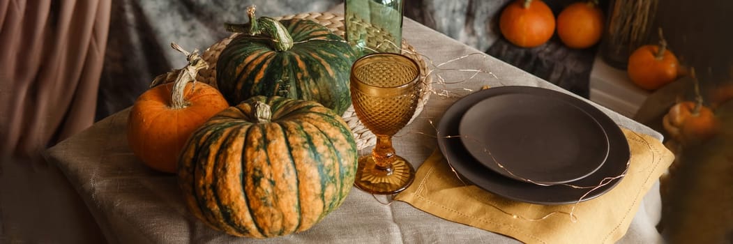 Autumn interior: a table covered with dishes, pumpkins, a relaxed composition of Japanese pampas grass. Interior in the photo Studio. Close - up of a decorated autumn table