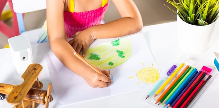 Asian cute kid preschooler sit on table smiling she draw picture with pencil at home, Happy child little girl colorful drawing family standing hold hands on planet earth on paper, earth day concept