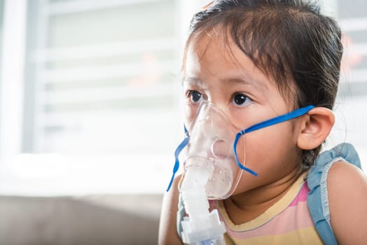 Kid girl making makes inhalation nebulizer steam sick cough at home, Asian Child using nebulizer mask equipment alone have smoke, stuffy nose and runny, oxygen spray inhaler therapy, Health medical
