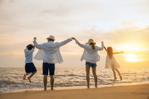 Silhouette of family holding hands live healthy lifestyle on beach, Happy Asian family have fun jumping together on beach in holiday sunset time, Back people enjoying travel trip and summer vacations