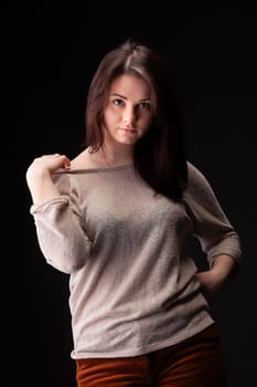 A female model stands poised in a studio, showcasing confidence and elegance. She wears a light sweater and interacts playfully with her clothing, creating a striking visual effect.