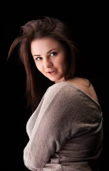 A young woman showcases her flowing hair while turning slightly to the side, wearing a soft, casual top. The dark background enhances her facial features and expression.