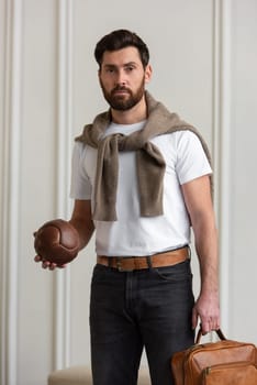 A fashionable man stands with a yellow brown backpack in a contemporary room, embodying urban style and professionalism.