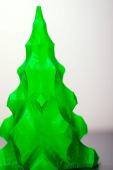 A vibrant green, threedimensional printed Christmas tree is elegantly positioned on a table, adding a festive touch to the surroundings