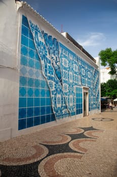 pedestrian path in the city of Lagos, Portugual, passing by a building covered by white and blue ceramic