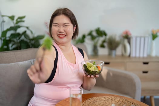 A cheerful woman embraces healthy eating in her cozy home focusing on losing weight with nutritious food.