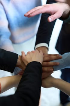 A top view of business people joining hands in a circle, symbolizing unity, collaboration, and shared success in the workplace.