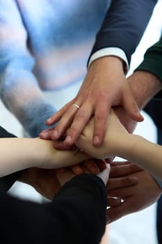 A top view of business people joining hands in a circle, symbolizing unity, collaboration, and shared success in the workplace.