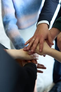 A top view of business people joining hands in a circle, symbolizing unity, collaboration, and shared success in the workplace.