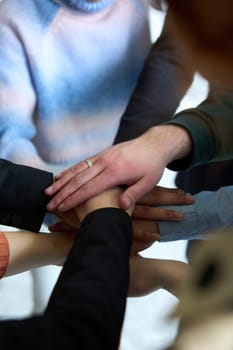 A top view of business people joining hands in a circle, symbolizing unity, collaboration, and shared success in the workplace.