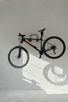 A mountain bike hanging on a white wall in garrage.