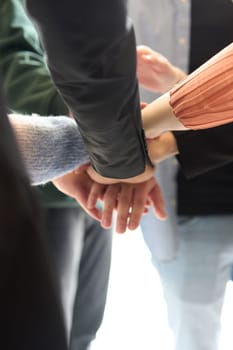 A top view of business people joining hands in a circle, symbolizing unity, collaboration, and shared success in the workplace.