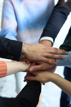 A top view of business people joining hands in a circle, symbolizing unity, collaboration, and shared success in the workplace.