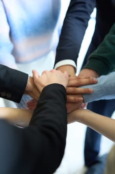 A top view of business people joining hands in a circle, symbolizing unity, collaboration, and shared success in the workplace.