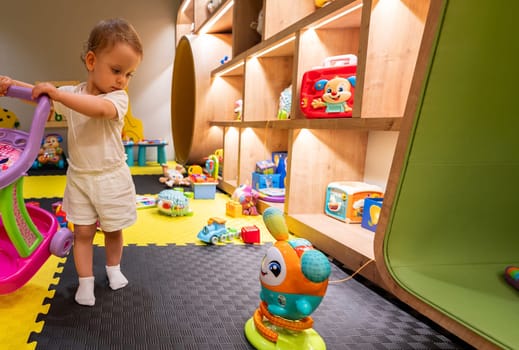 Little child exploring a cheerful and colorful playroom filled with fun and educational toys. Concept of child-friendly spaces and joyful learning