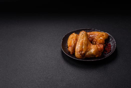Grilled chicken wings with salt and spices on dark concrete background