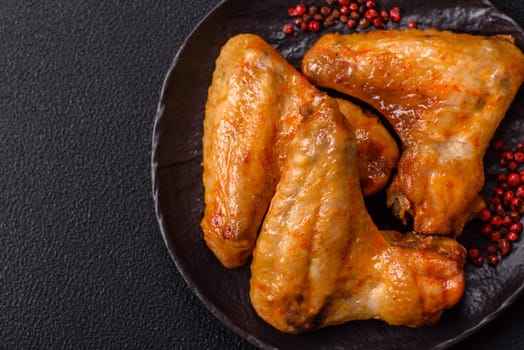 Grilled chicken wings with salt and spices on dark concrete background