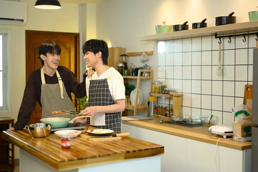 Joyful gay couple enjoys cooking together in their cozy kitchen.